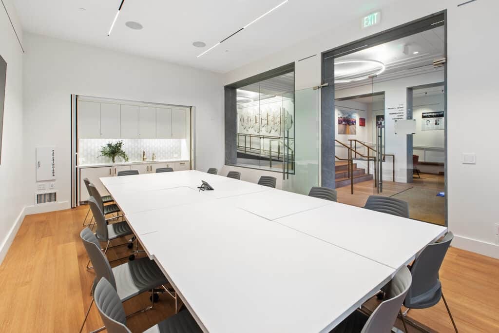 Conference room with a long meeting table and glass doors opening toward the lobby
