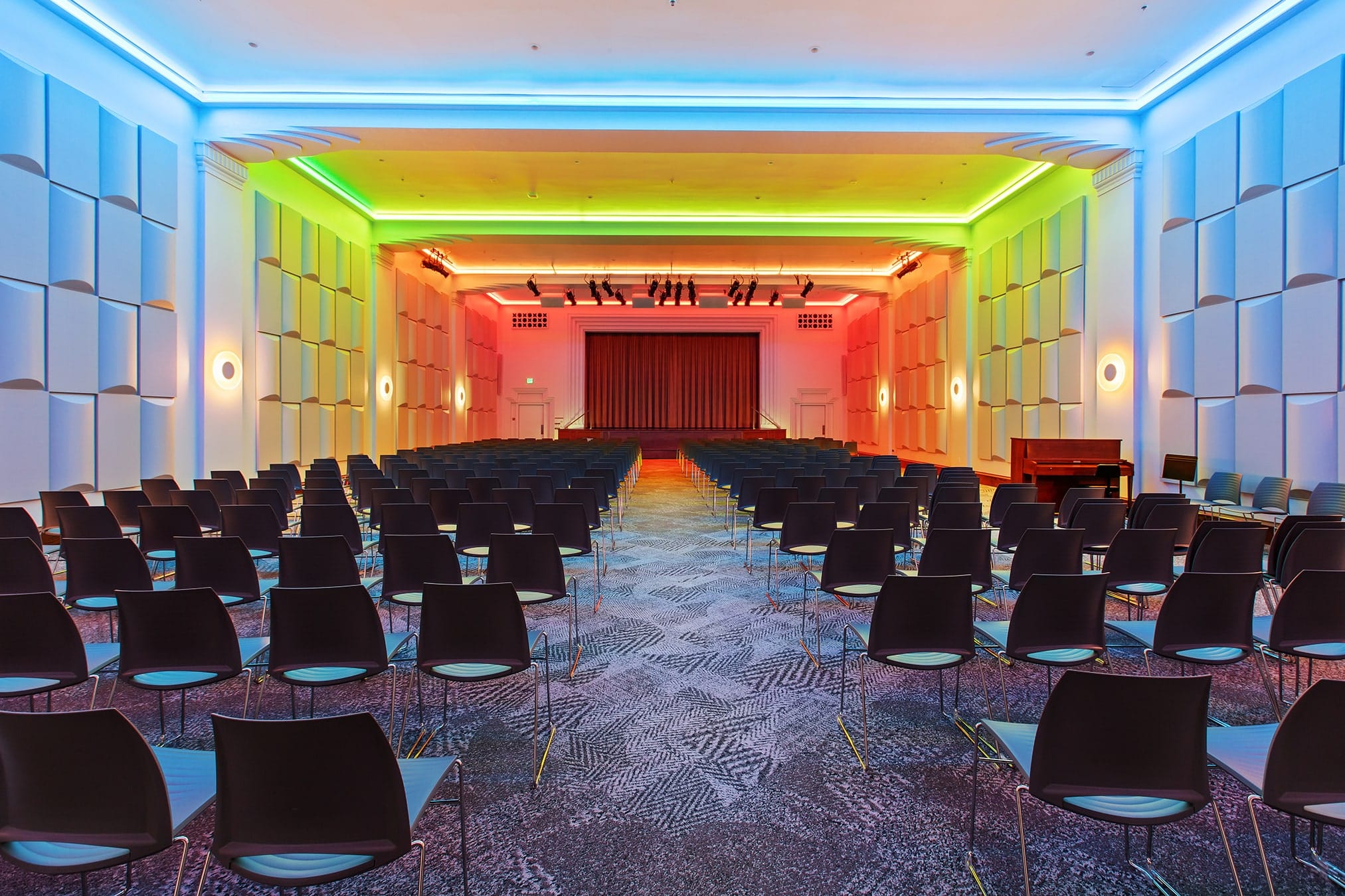 Grand Hall with audience seating, a stage and colorful architectural lighting